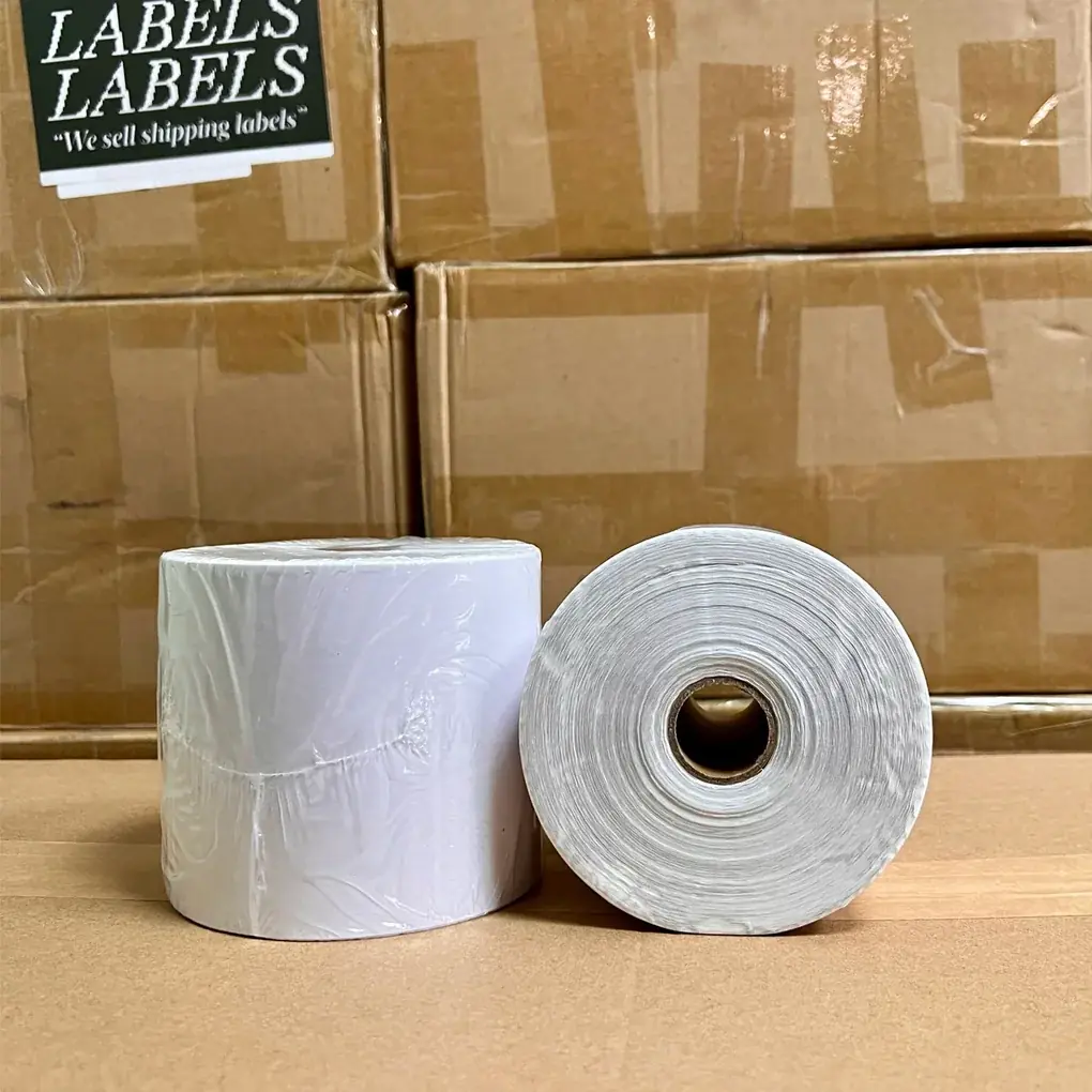 Two rolls of LabelsLabels thermal shipping labels stacked in front of branded boxes in the warehouse.