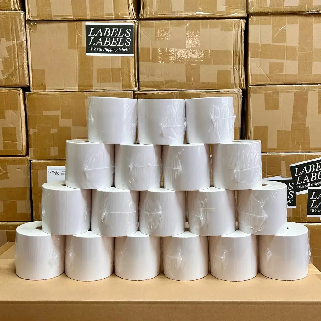 A pyramid stack of eighteen rolls of LabelsLabels thermal labels, ready to ship, in front of branded boxes in the London warehouse.